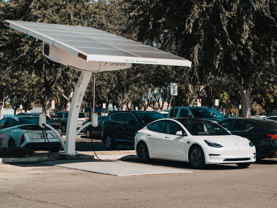 Ombrière à panneaux solaires au-dessus d'un parking où une voiture blanche est garée